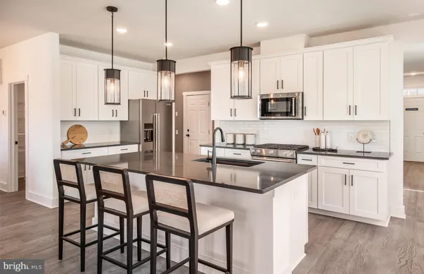 a kitchen with stainless steel appliances granite countertop a stove a sink a refrigerator and white cabinets with wooden floor