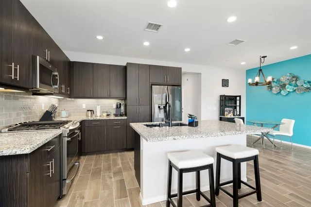 a kitchen with kitchen island granite countertop a sink and stainless steel appliances