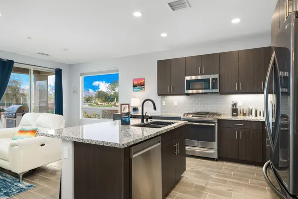 a kitchen with stainless steel appliances granite countertop a sink stove refrigerator and cabinets