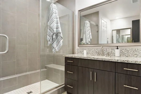 a bathroom with a granite countertop sink a mirror and a shower