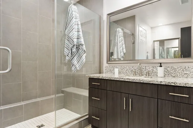 a bathroom with a granite countertop sink a mirror and a shower
