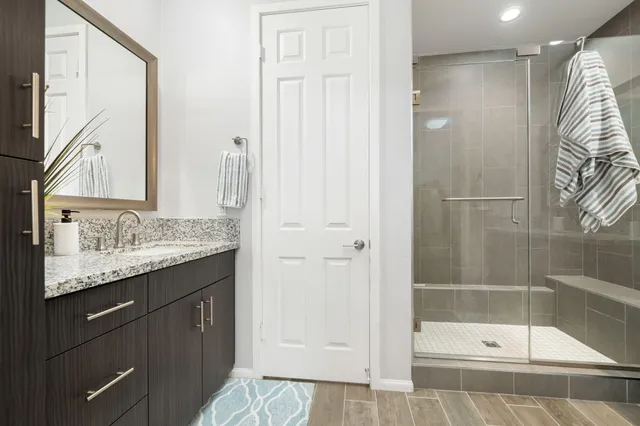 a bathroom with a granite countertop sink a mirror and a shower
