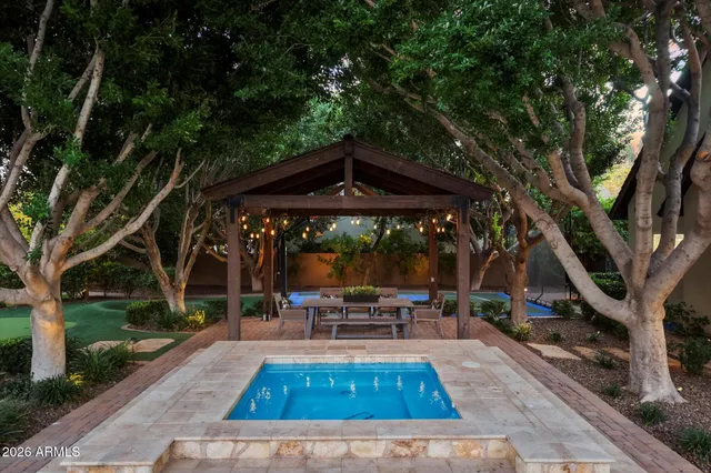a view of patio with table and chairs under an umbrella with large trees