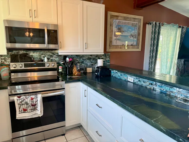 a kitchen with stainless steel appliances granite countertop a stove a sink and a microwave