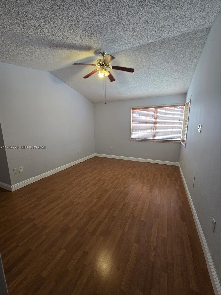 14611 Balgowan Road, Unit 2041 Miami Lakes, FL 33016 - Photo 9 of 22 an empty room with wooden floor chandelier fan and windows