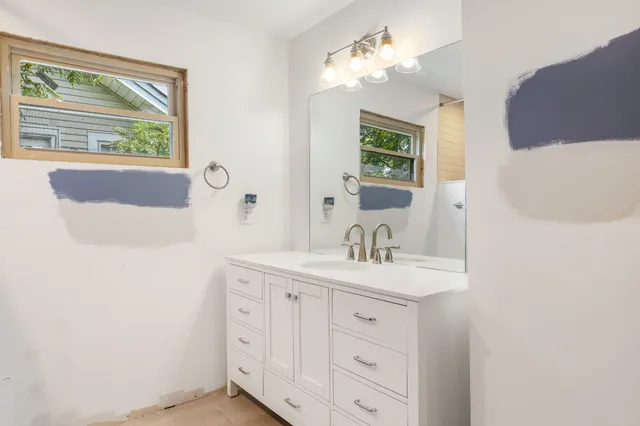 a bathroom with a sink a large mirror and a window
