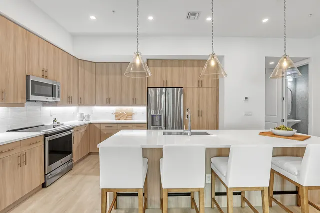 a kitchen with stainless steel appliances kitchen island granite countertop a stove a sink a refrigerator with a dining table and chairs