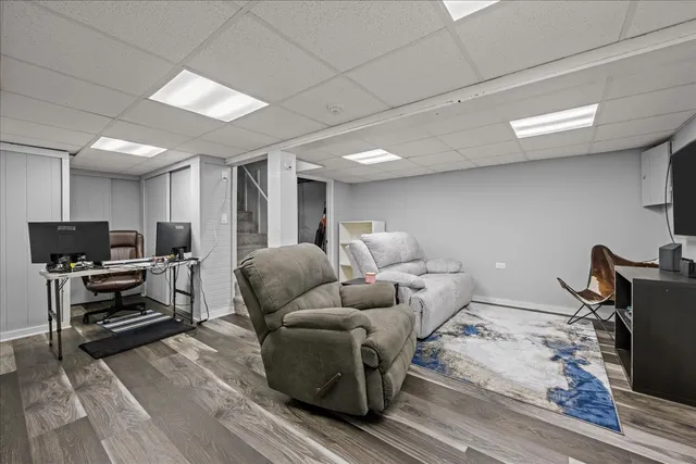 a living room with furniture a flat screen tv and a refrigerator