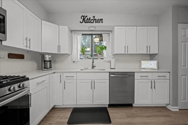a kitchen with white cabinets white stainless steel appliances and sink