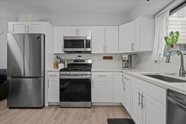 a kitchen with cabinets stainless steel appliances a sink and wooden floor