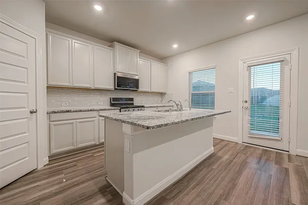 a kitchen with granite countertop a sink cabinets and stainless steel appliances