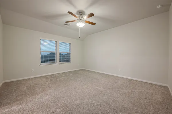 an empty room with chandelier fan and windows
