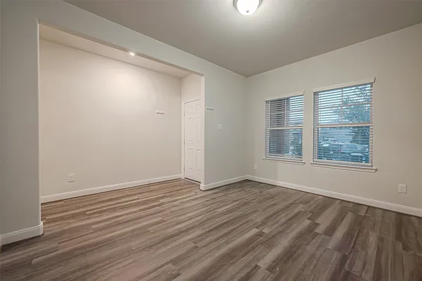 a view of an empty room with wooden floor and a window