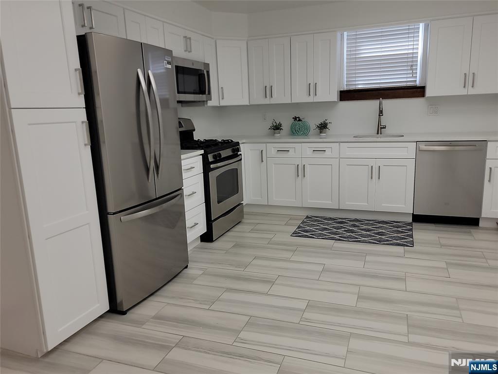 a kitchen with stainless steel appliances a refrigerator sink and microwave