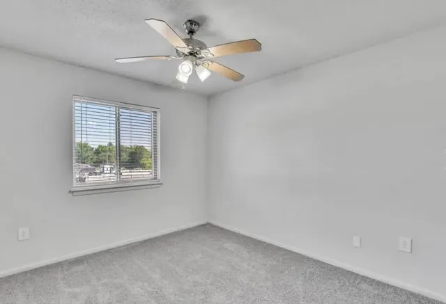 an empty room with a window and a fan