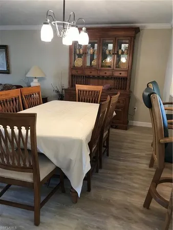 a dining room with wooden floor a chandelier a wooden table and chairs