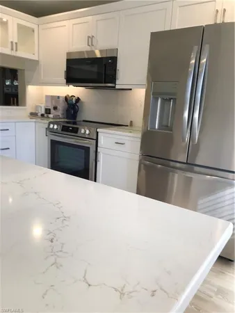 a kitchen with granite countertop a refrigerator stove and sink