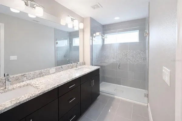 a bathroom with a granite countertop sink mirror and shower
