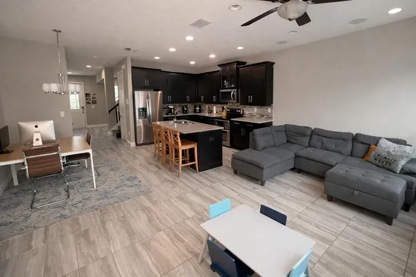 a living room with couches kitchen view and a kitchen island