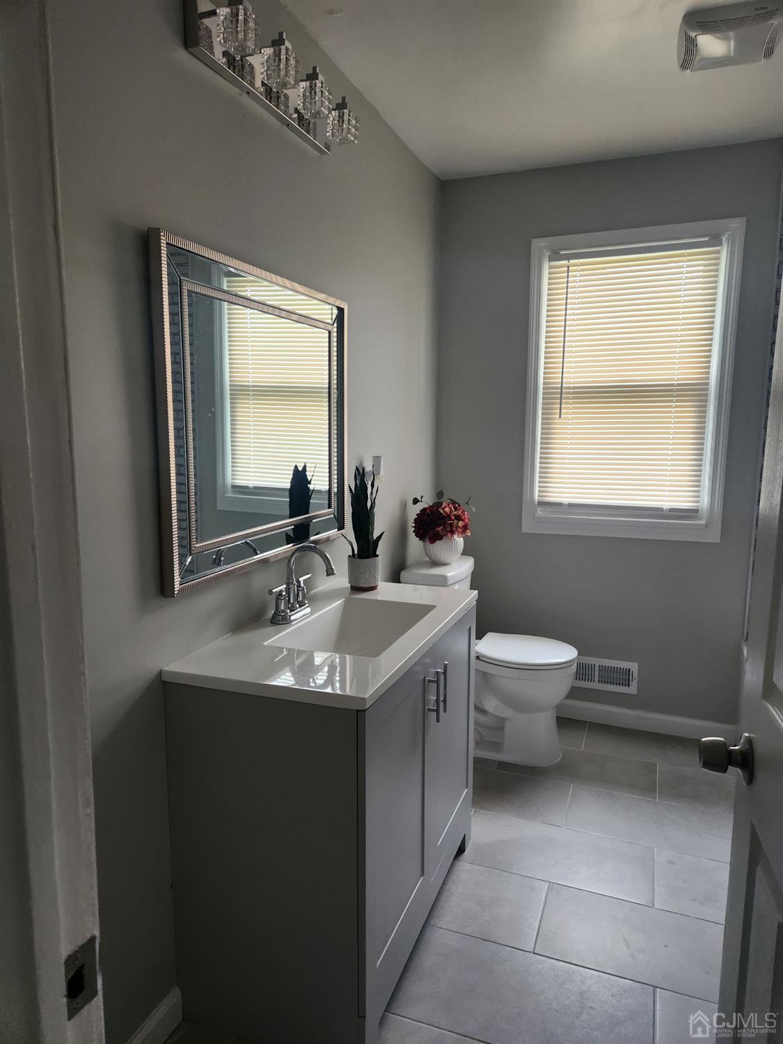 190 Berkeley Terrace Plainfield, NJ 07062 - Photo 5 of 23 a bathroom with a granite countertop toilet a sink a mirror and a window