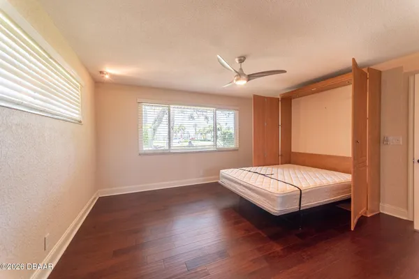 an empty room with chandelier fan and windows