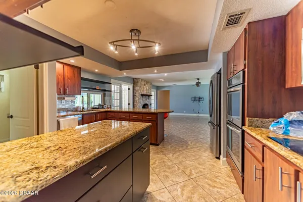 a room with stainless steel appliances kitchen island granite countertop furniture and a refrigerator