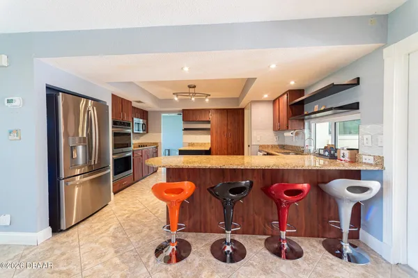 a kitchen with a sink refrigerator and chairs
