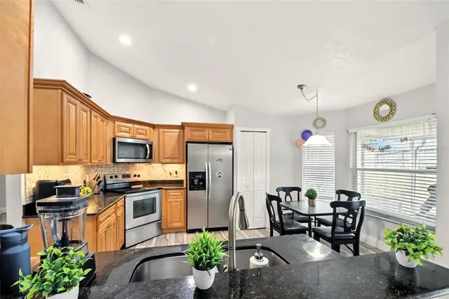 a kitchen with stainless steel appliances kitchen island granite countertop a stove top oven a sink a dining table and chairs