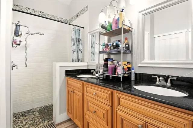 a bathroom with a granite countertop sink a mirror and shower