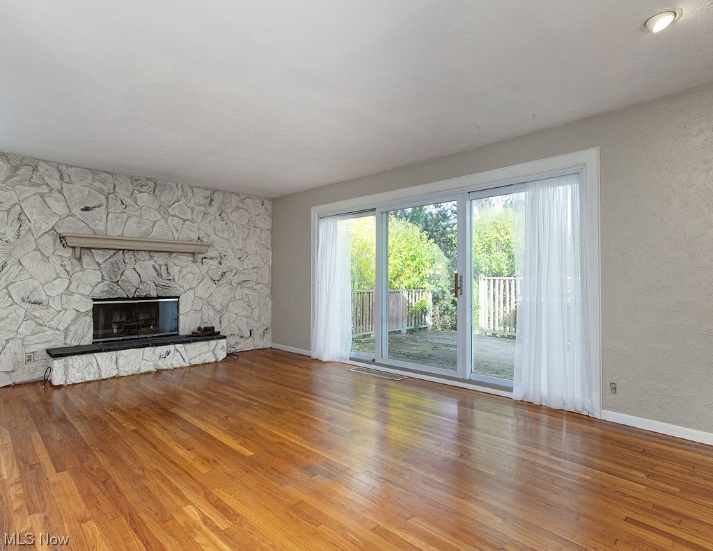 4897 South Sedgewick Road Cleveland, OH 44124 - Photo 2 of 31 Unfurnished living room featuring light hardwood floors, fireplace, and deck access