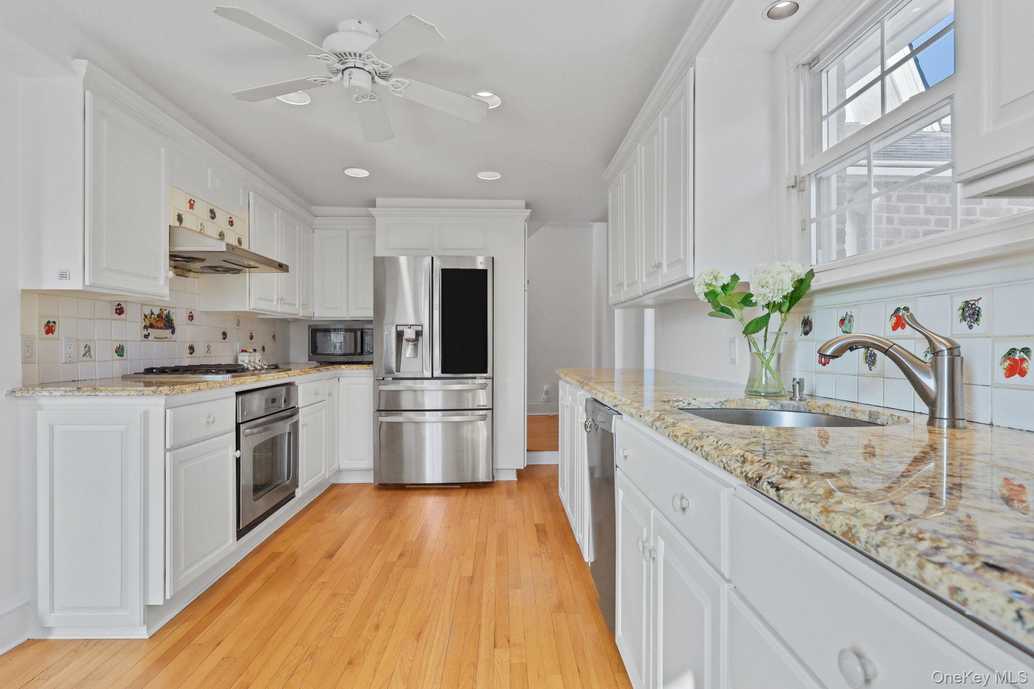 401 Heathcote Road Scarsdale, NY 10583 - Photo 13 of 41 a kitchen with stainless steel appliances granite countertop a white refrigerator a sink dishwasher a oven with white cabinets and wooden floor