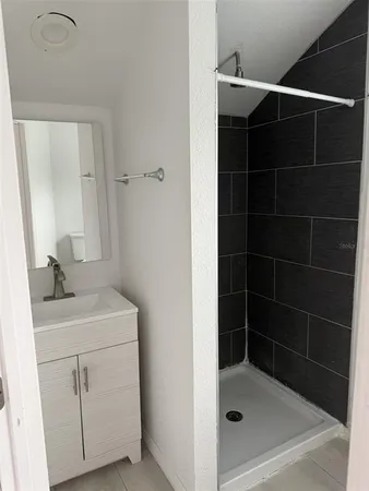a bathroom with a shower a sink and mirror
