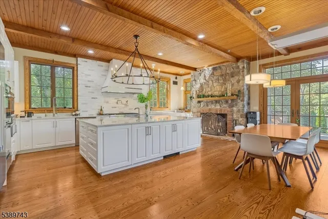 a room with stainless steel appliances kitchen island granite countertop a table chairs and a large window