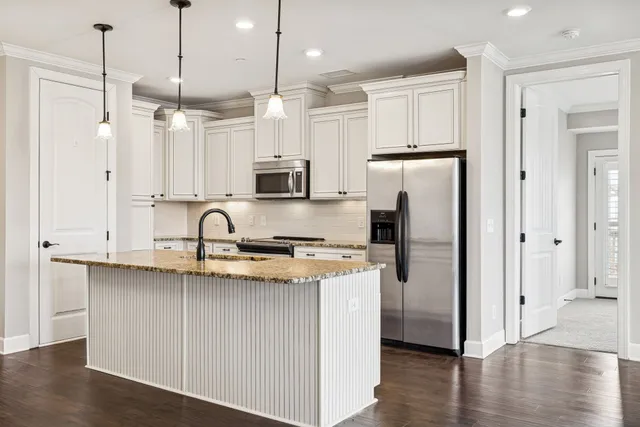 a kitchen with stainless steel appliances granite countertop a refrigerator a sink a stove and a wooden floors