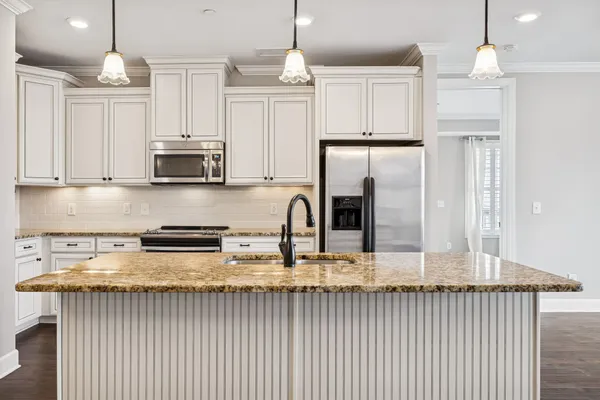 a kitchen with stainless steel appliances granite countertop a stove a sink and white cabinets