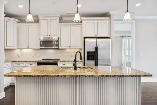 a kitchen with stainless steel appliances granite countertop a stove a sink and white cabinets