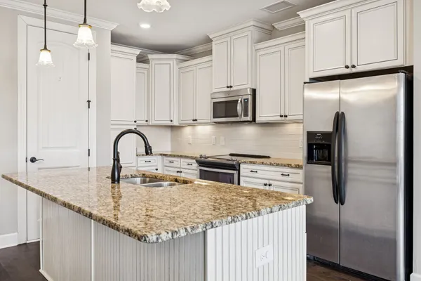 a kitchen with stainless steel appliances granite countertop a sink a stove a refrigerator a center island and cabinets