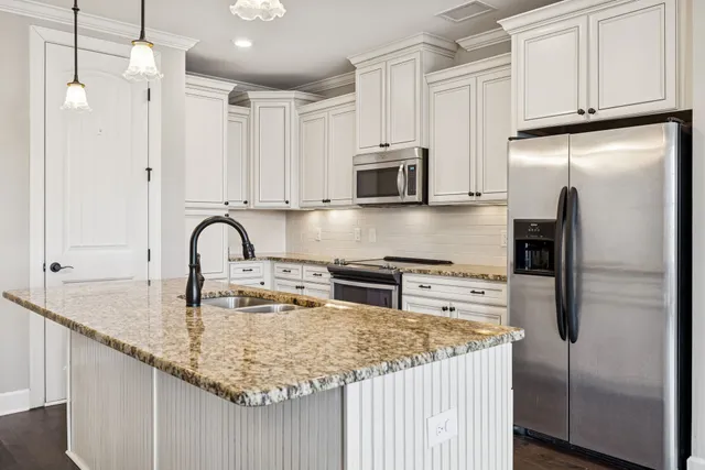 a kitchen with stainless steel appliances granite countertop a sink a stove a refrigerator a center island and cabinets
