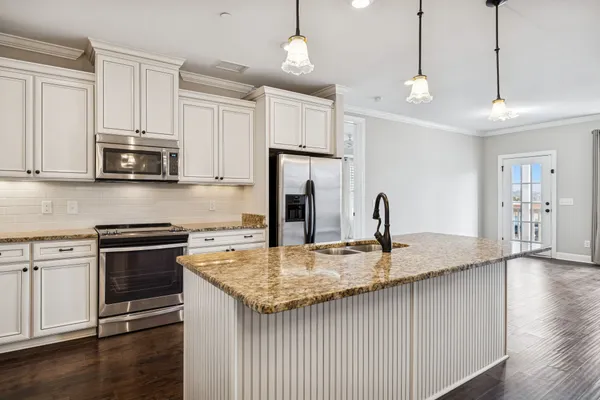 a kitchen with stainless steel appliances granite countertop a sink a stove and a refrigerator