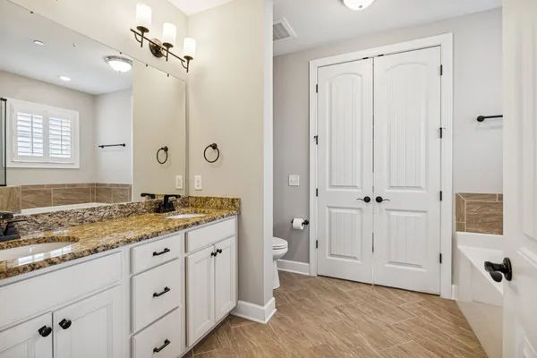 a bathroom with a granite countertop sink a mirror and a bathtub