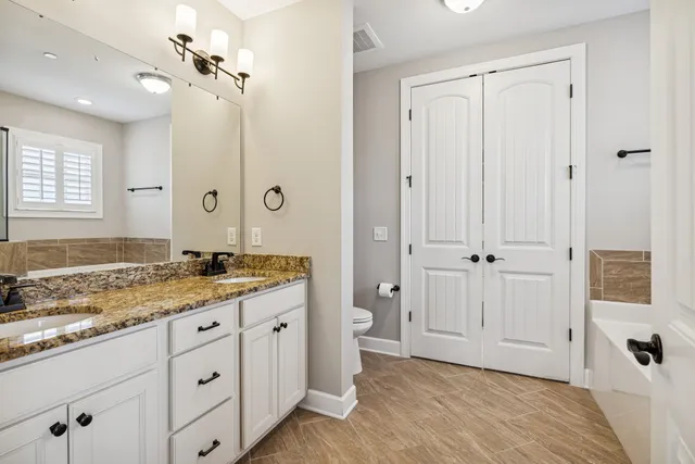 a bathroom with a granite countertop sink a mirror and a bathtub