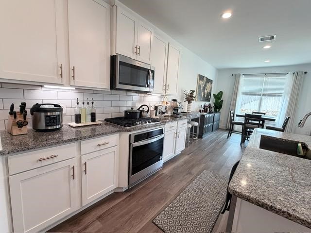 13725 Rising Sun Lane Conroe, TX 77384 - Photo 9 of 29 a kitchen with granite countertop a sink a stove top oven and cabinetry