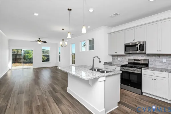 a large kitchen with stainless steel appliances granite countertop a stove a sink dishwasher a microwave oven with cabinets and wooden floor