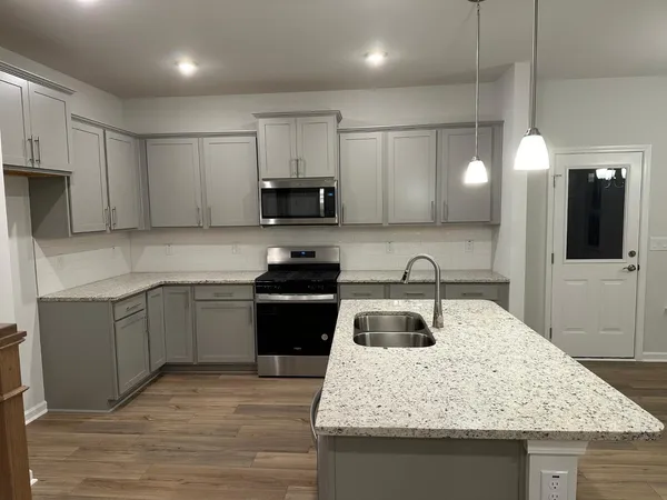 a kitchen with kitchen island granite countertop a sink stainless steel appliances and white cabinets