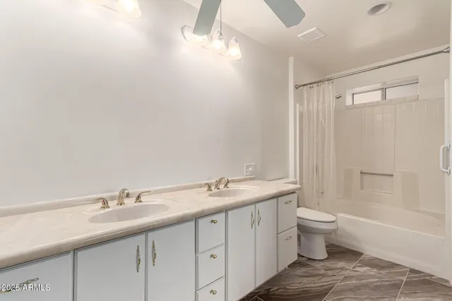 a bathroom with a granite countertop sink a toilet and shower