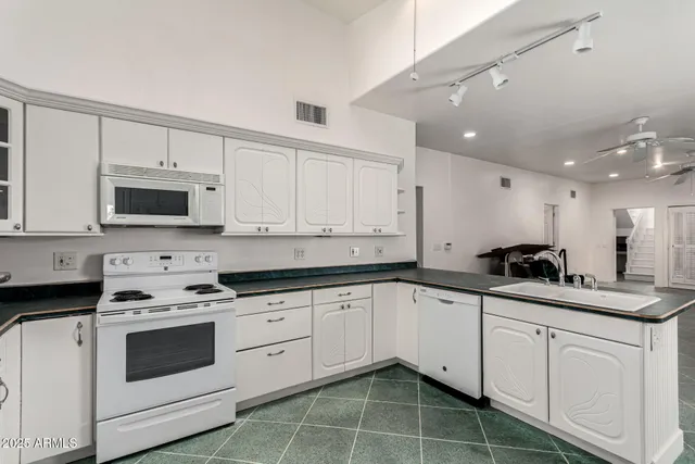 a kitchen with granite countertop white cabinets white stainless steel appliances with a sink and dishwasher