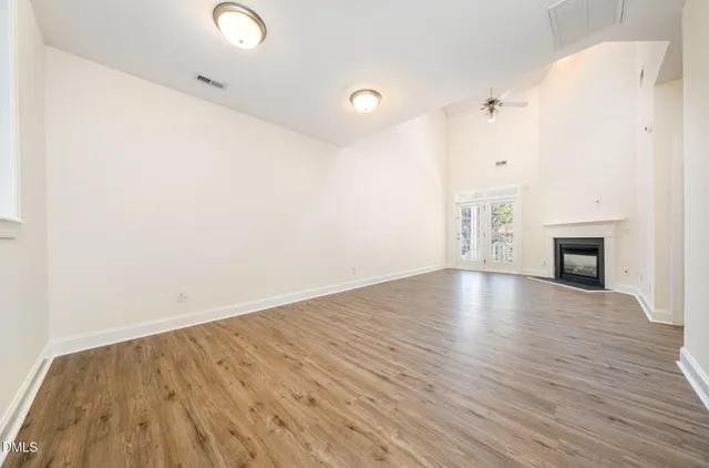 a view of empty room with wooden floor and fireplace