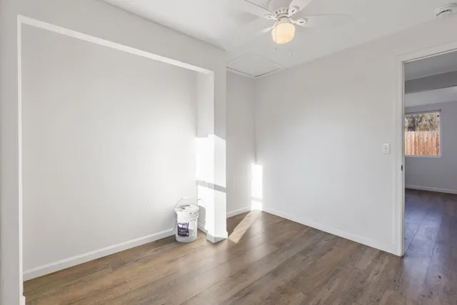 an empty room with wooden floor and fan