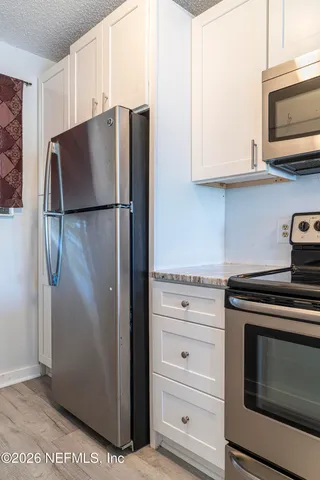 a kitchen with stainless steel appliances white cabinets and a refrigerator