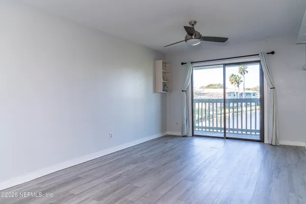 a view of an empty room with wooden floor and a window